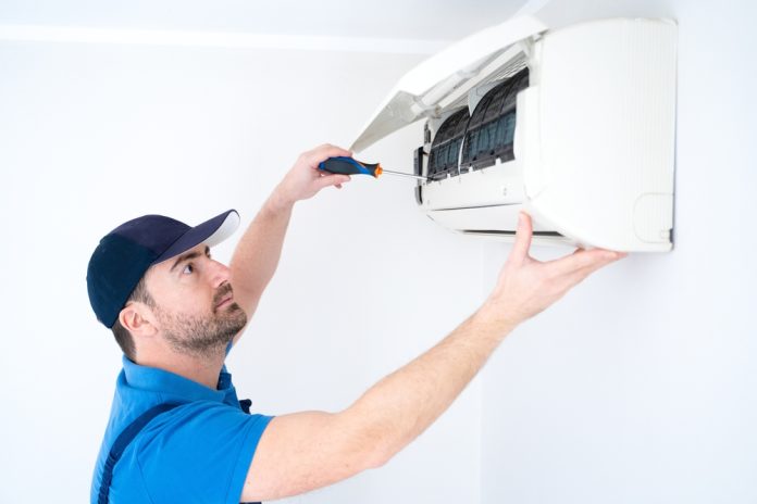 Technician,Installing,Air,Conditioner,On,The,Wall,At,Home,For